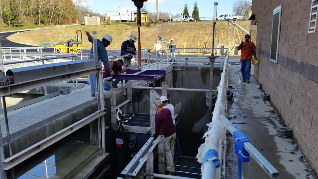 Industrial water treatment facility with workers installing equipment at MMBR Systems site.