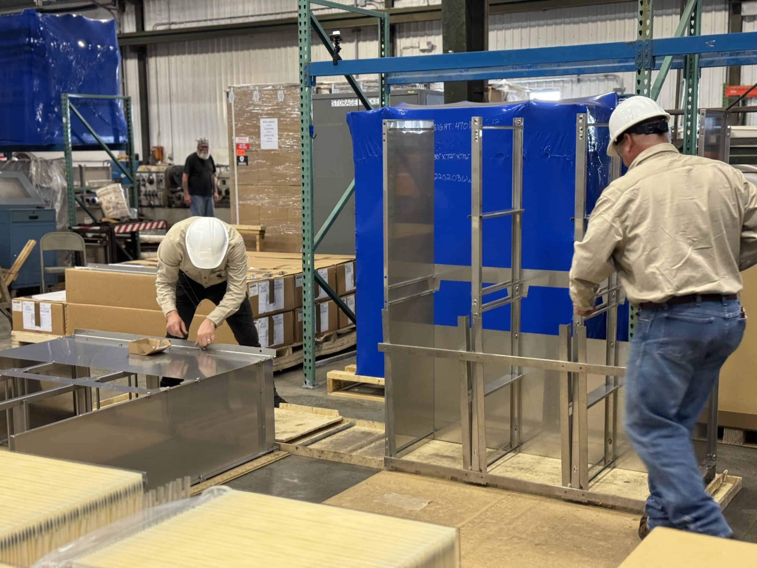 Workers assembling stainless steel equipment in a manufacturing plant.