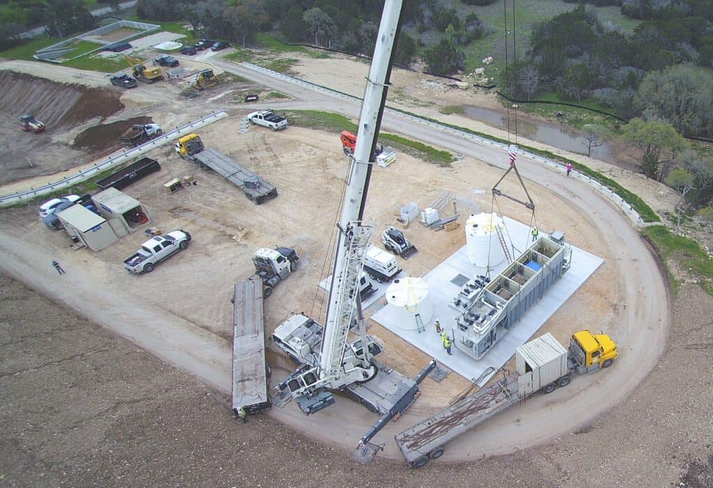 Heavy construction site with crane lifting equipment and vehicles at a project location.