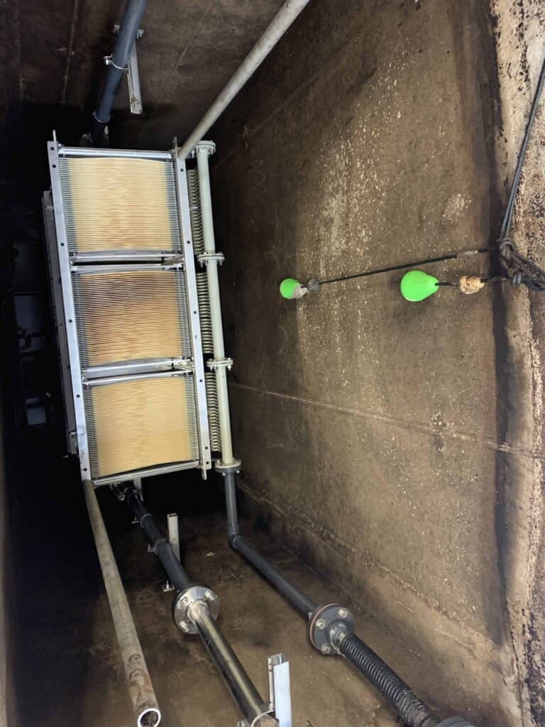 Industrial filtration system with pipes and green float sensors in a concrete setting.
