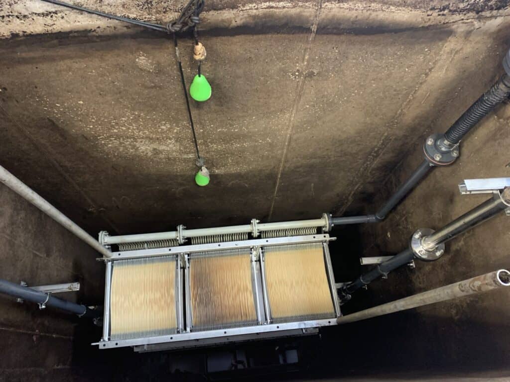 Industrial filtration system with pipes and green float sensors in a concrete setting.