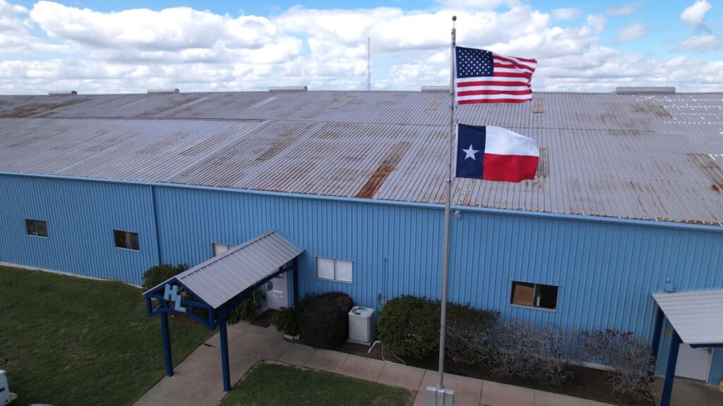 MMBR Systems industrial building with American and Texas flags, clear sky, and outdoor setting.