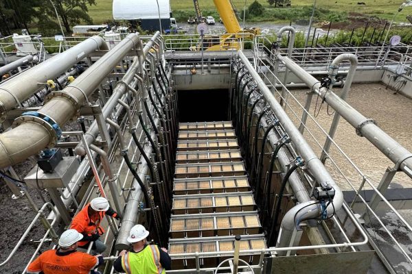Industrial water treatment facility with engineers inspecting equipment and large crane in backgroun.