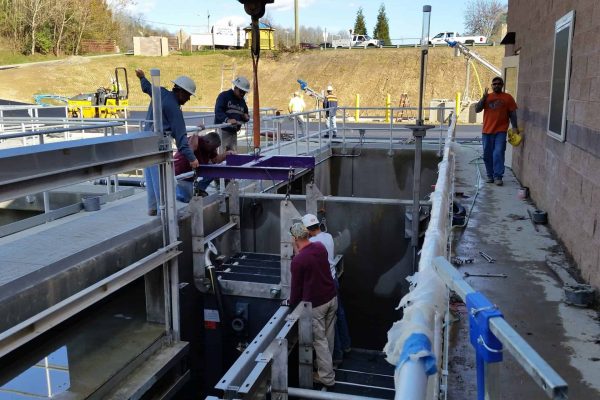 Industrial water treatment facility with workers installing equipment at MMBR Systems site.