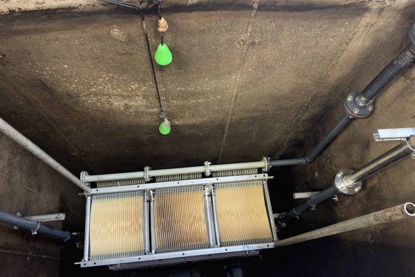 Industrial filtration system with pipes and green float sensors in a concrete setting.