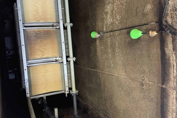 Industrial filtration system with pipes and green float sensors in a concrete setting.